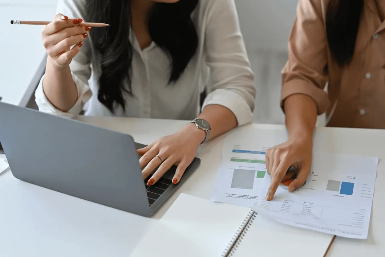 Two marketers discussing charts and data in front of a laptop — representing collaborative analysis for data-driven campaign optimisation.