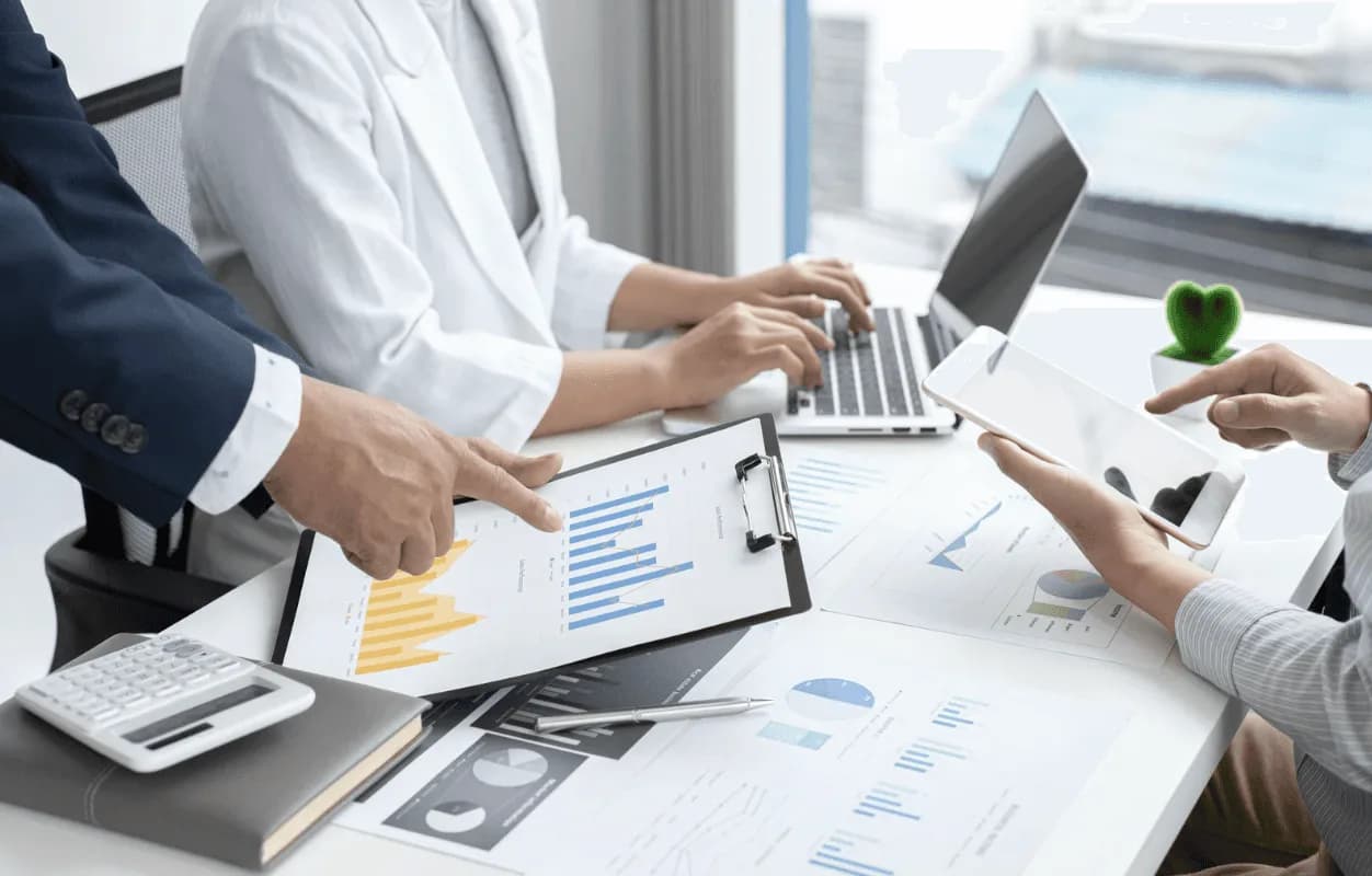 Team of marketers collaborating over charts and tablets to align Amazon ad spend, organic ranking, and external traffic sources