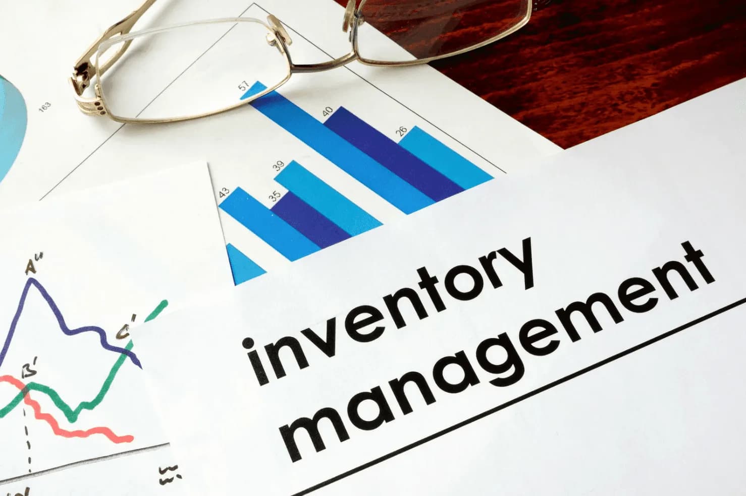 Inventory management charts and graphs on paper with glasses placed on top, symbolizing automated stock tracking and optimization.
