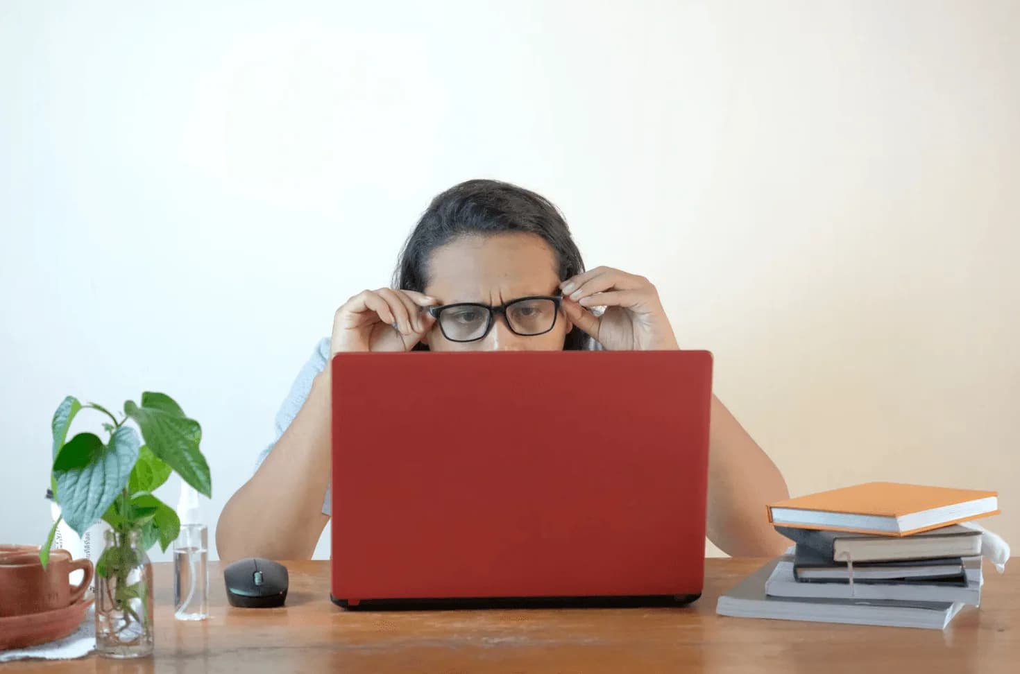 Marketer squinting at red laptop with books stacked beside them—illustrating the inefficiency of running Amazon ad campaigns in silos.