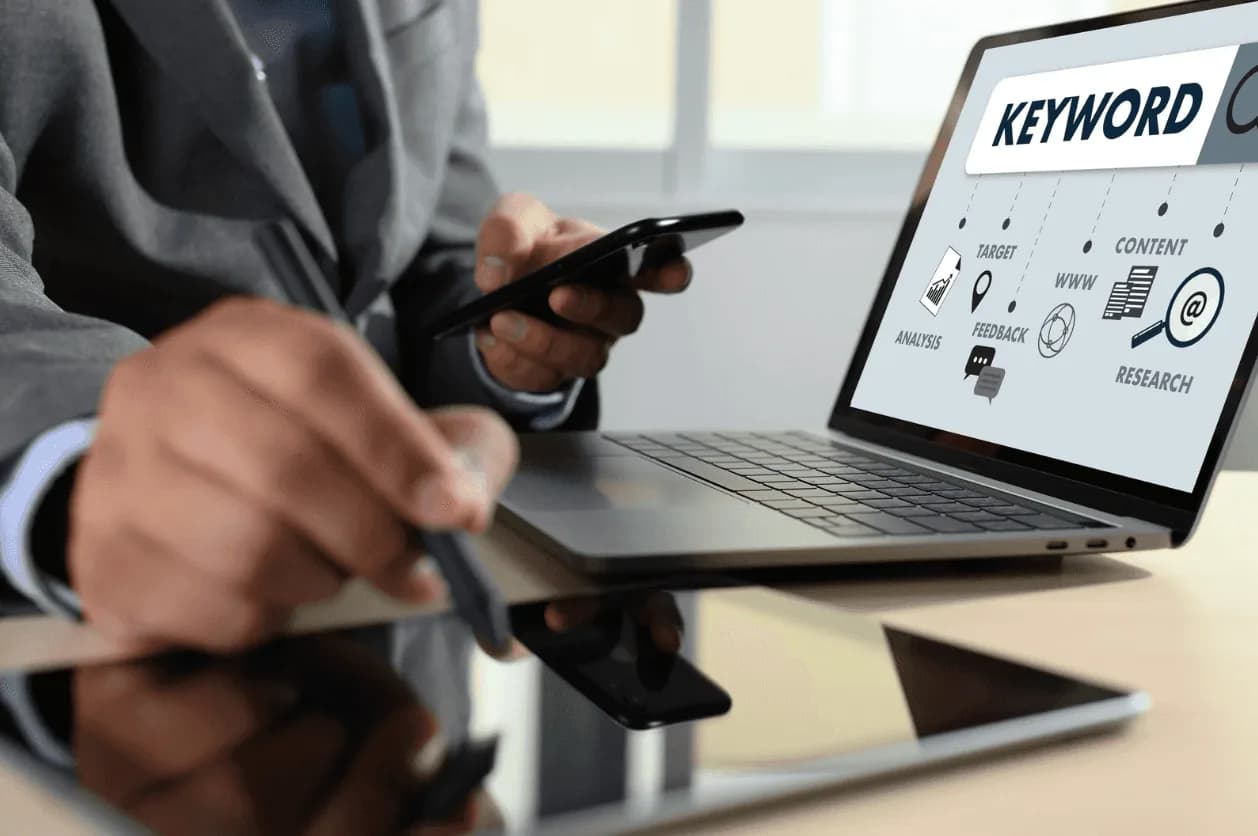 Close-up of Amazon keyword research dashboard on laptop with pen and smartphone – optimising keyword strategy to boost Amazon sales and prevent ad cannibalization