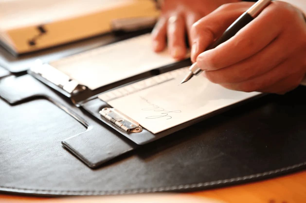 Close-up of a hand signing a contract on a clipboard – illustrating how external factors like tariffs impact Amazon ad strategies.