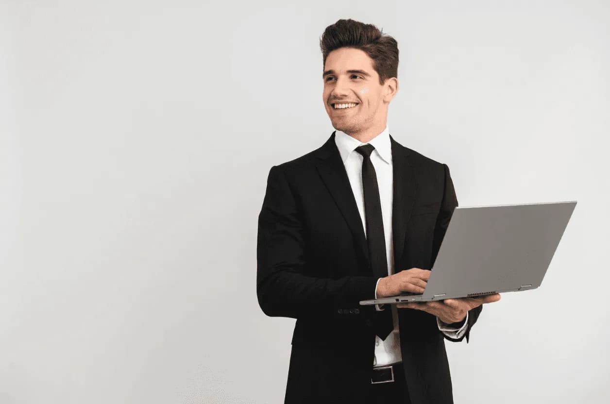 Confident businessman in a black suit using a laptop, representing modern PPC professionals embracing technology and automation.