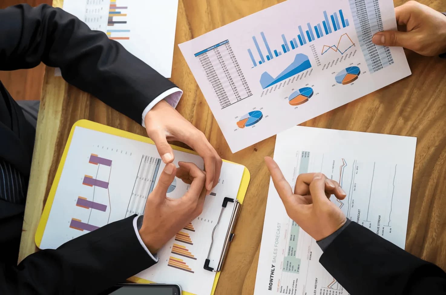 Business team reviewing charts and graphs on paper, discussing cross-campaign signals for Amazon PPC strategy optimisation.