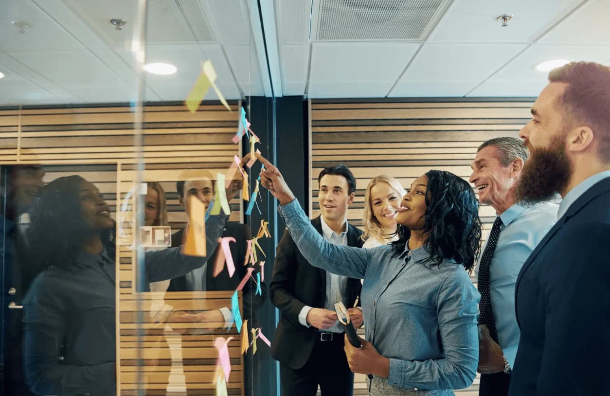 Business team brainstorming Amazon Ads optimisation ideas on a glass wall with colourful sticky notes.