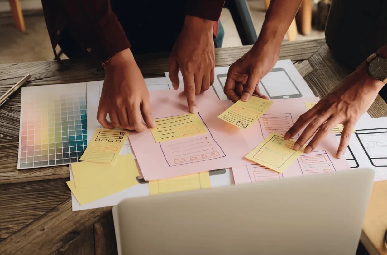 Marketeers collaborating on website wireframes using sticky notes and colour palette for UI/UX planning