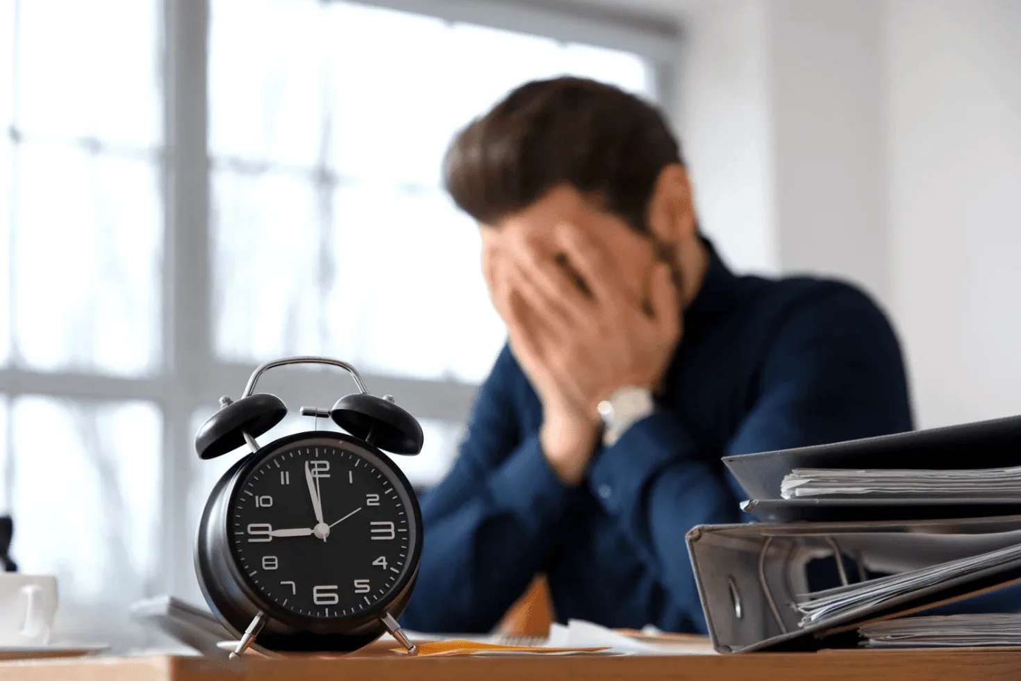 Stressed professional at a desk with a clock symbolising how slow, reactive Amazon ad services fall behind during scaling and peak seasons.