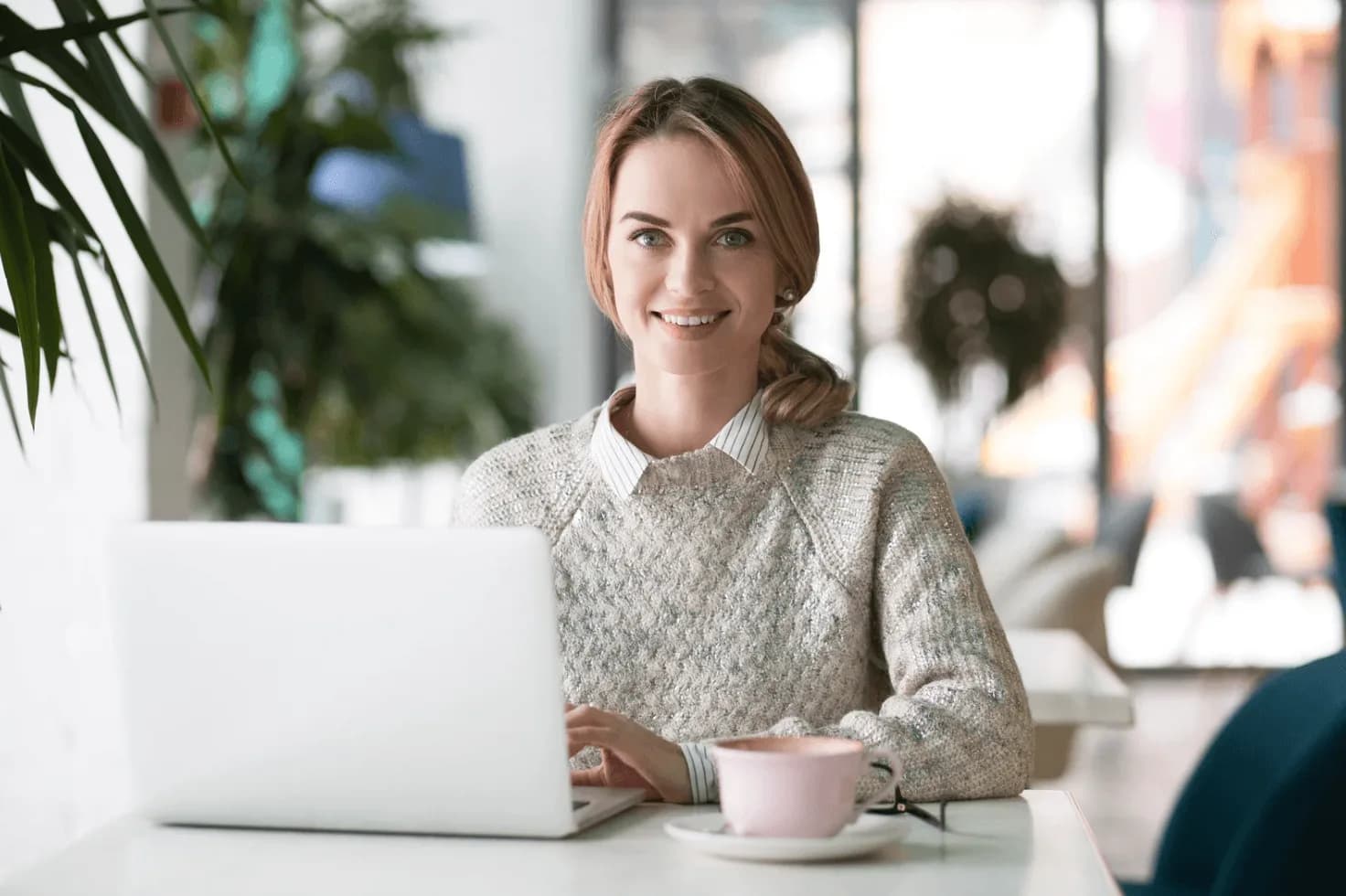 Woman working on a laptop in a café with a coffee cup, representing how Amazon sellers can win more Q4 sales with automation and less manual workload.