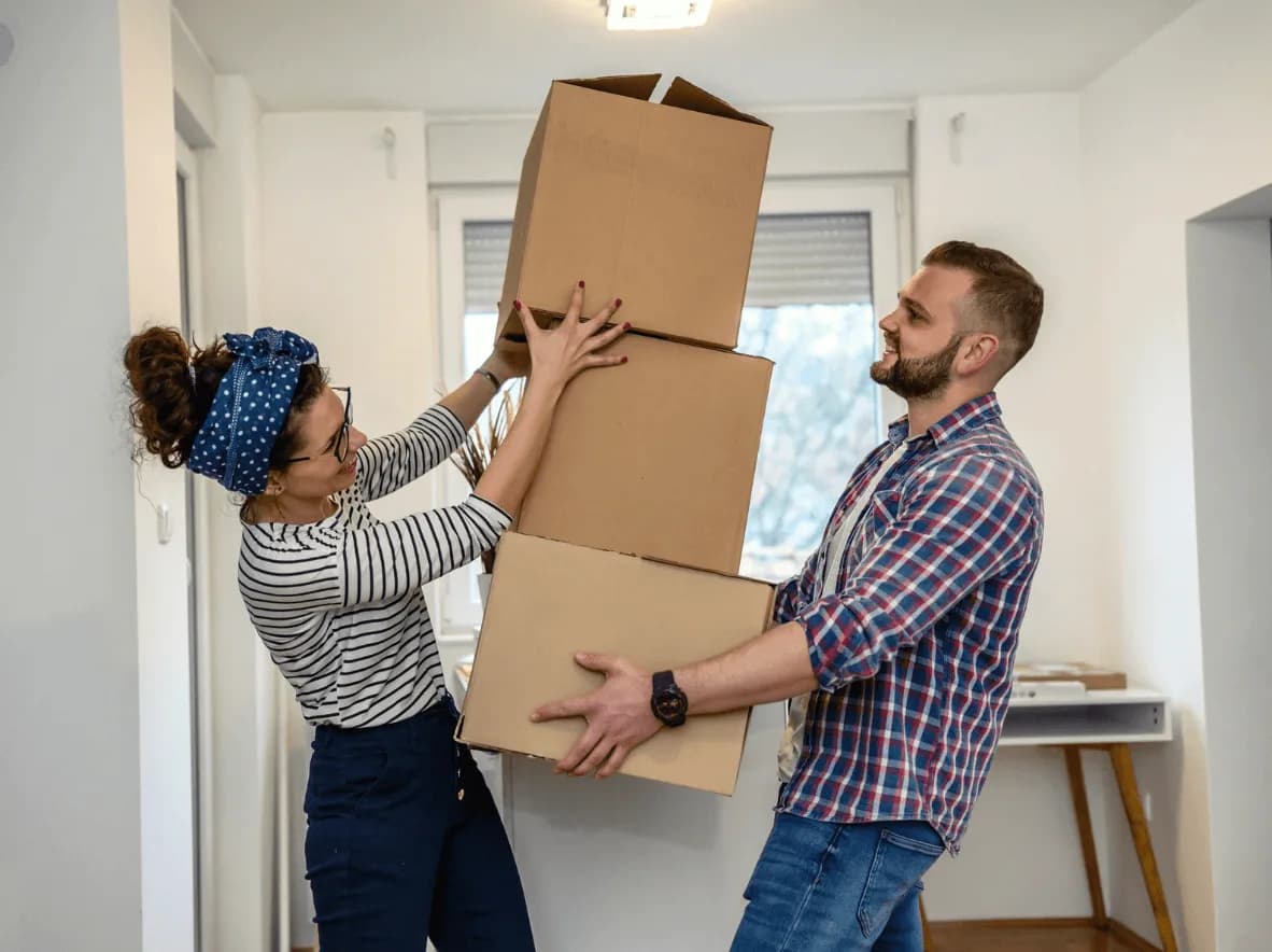 Couple carrying large moving boxes while setting up a new home or small business