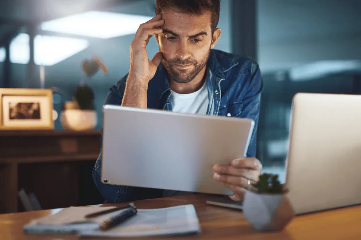 Focused entrepreneur reviewing e-commerce analytics on a tablet at night