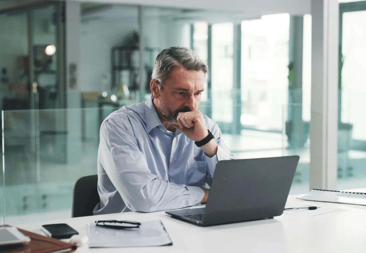 Middle-aged man in a bright office concentrating on his laptop, symbolising how manual oversight of high-value ASINs can slow response times—reinforcing the need for autonomous, real-time PPC management systems like Autron.