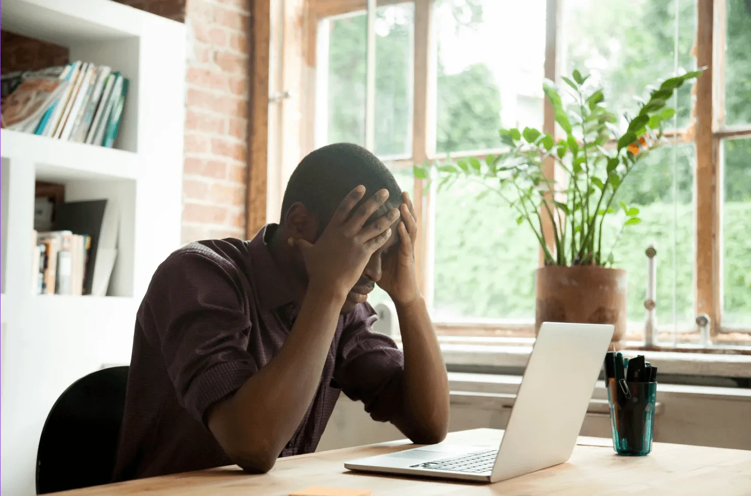 Professional appearing thoughtful at laptop, representing how Sponsored Products and Sponsored Brands require coordinated strategy to avoid inefficiency and wasted ad spend despite having distinct placements on Amazon.