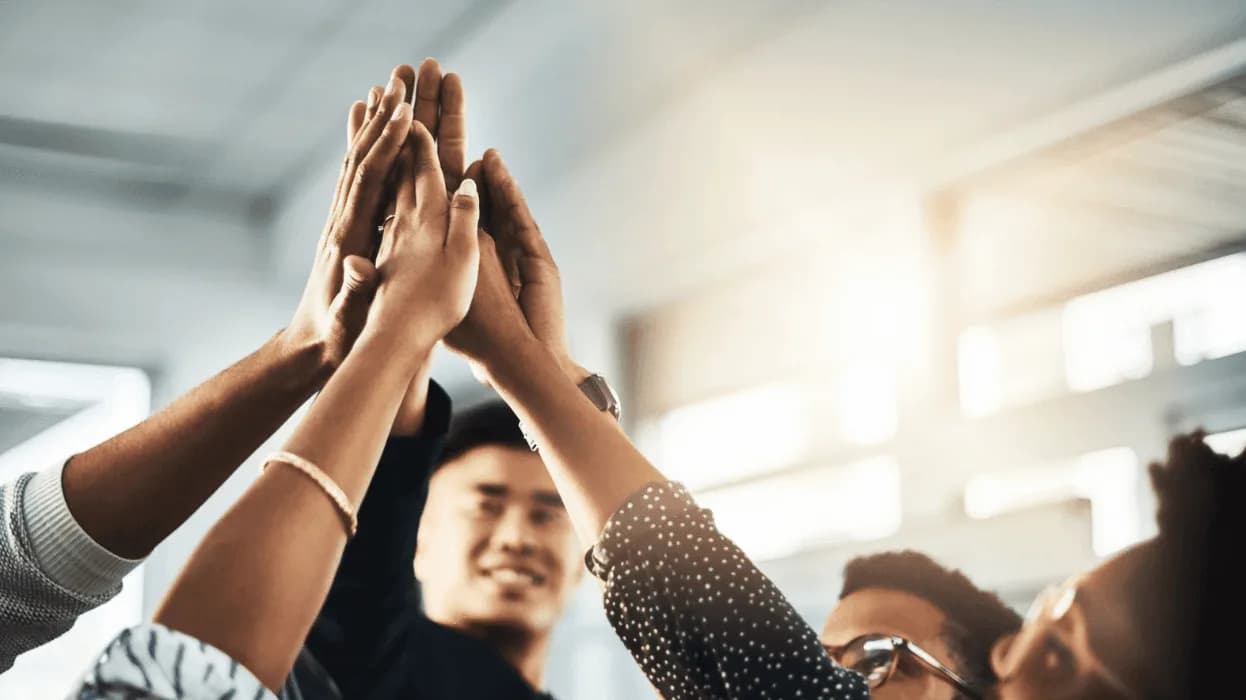 Diverse team celebrating success with high-fives after improving Amazon Ads performance