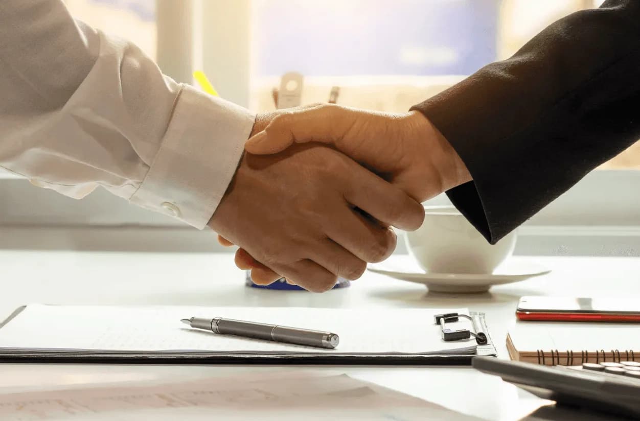 Business handshake over documents, depicting partnership strategies to navigate new Amazon tariff challenges