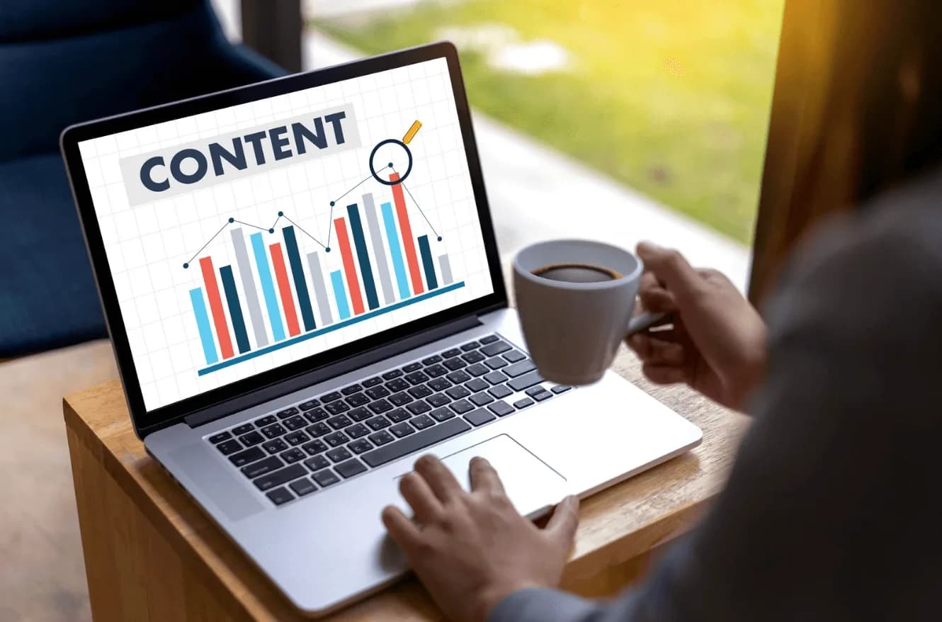 Marketer working on a laptop with a coffee cup, reviewing content performance graphs, highlighting how Autron simplifies staying competitive with Amazon PPC.