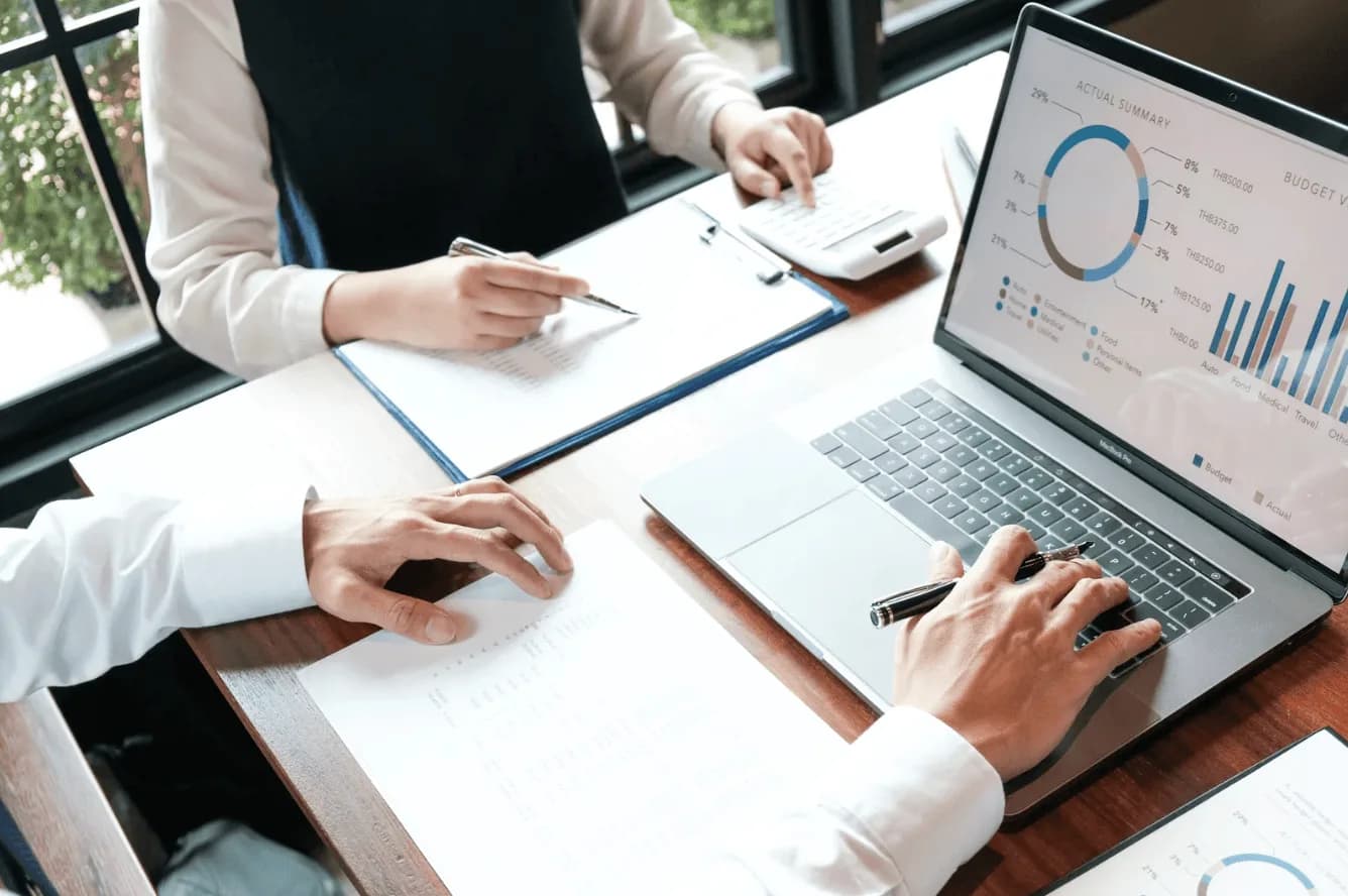 Business professionals analysing charts and data on a laptop, showing controlled Amazon PPC testing to minimise wasted spend.