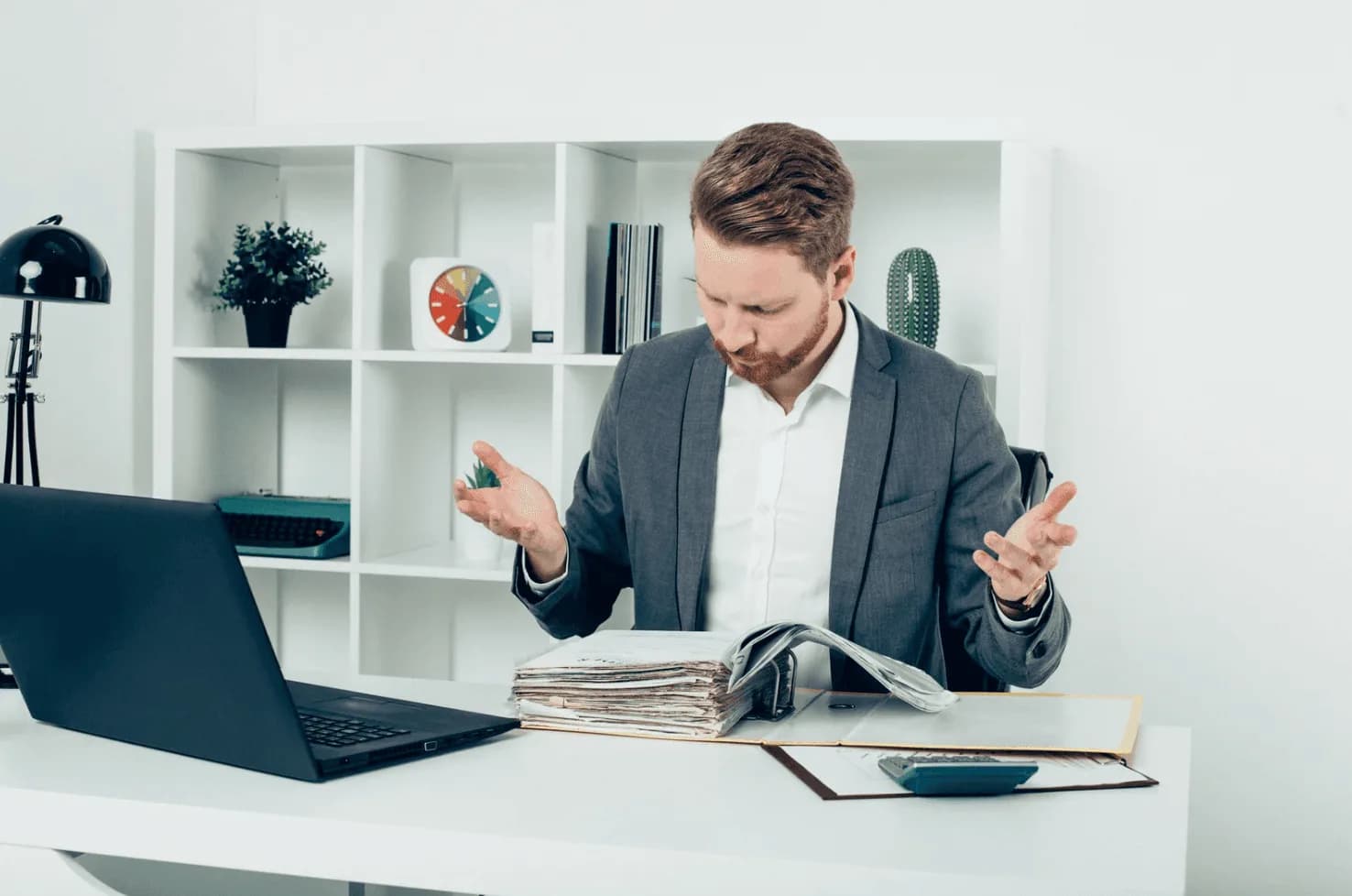 Frustrated businessman reviewing thick binders and reports — representing the challenge of scaling manual Amazon ad management.